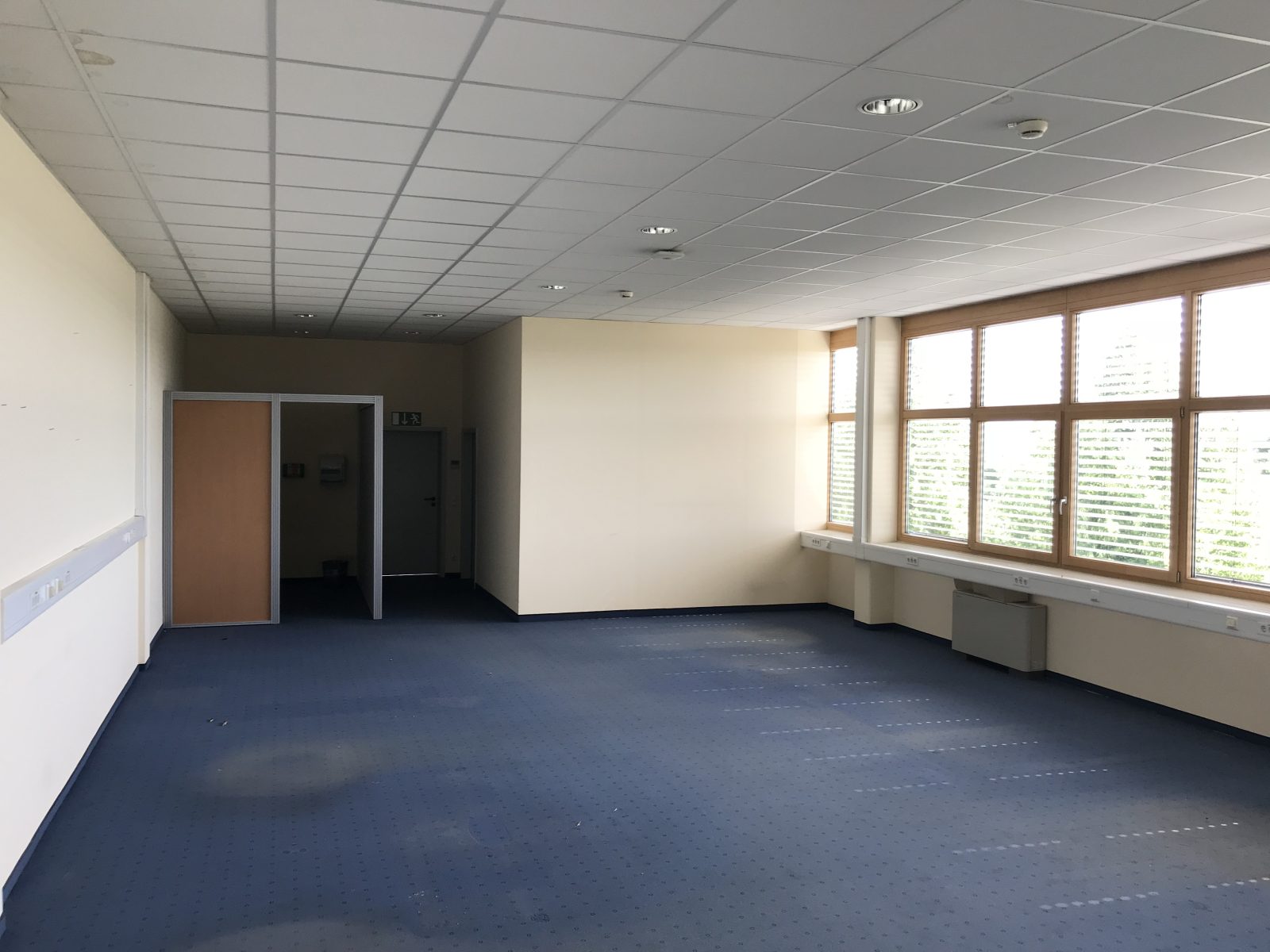 Open, unpartitioned commercial office floor with a suspended ceiling grid, ready for a drywall partition layout
