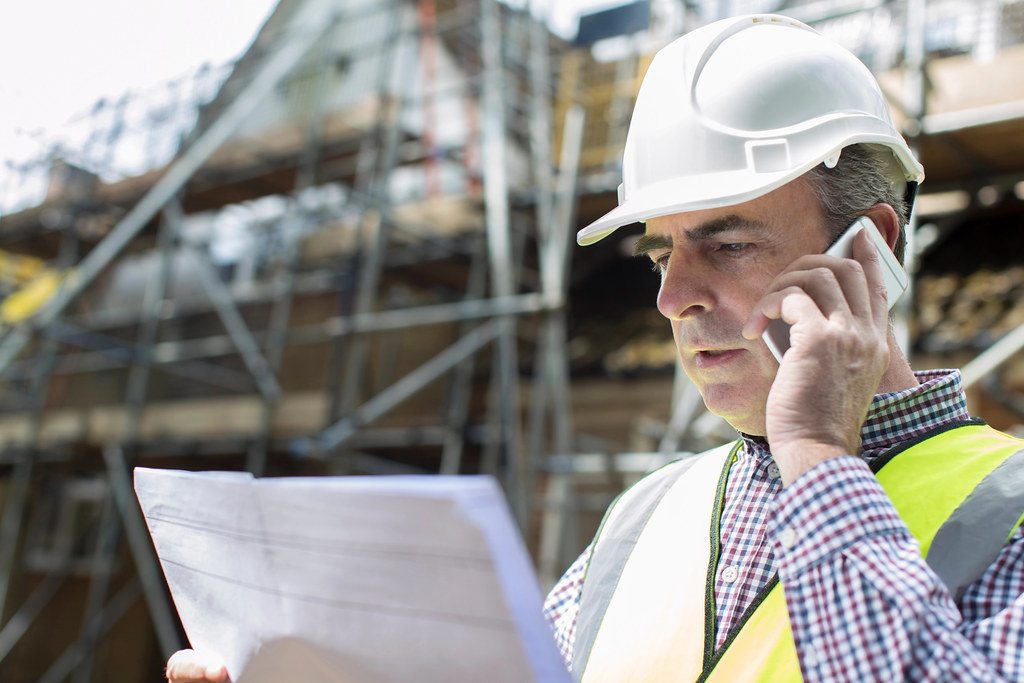 Site manager reviewing project costs on ERPNext via a mobile device at a UAE construction jobsite
